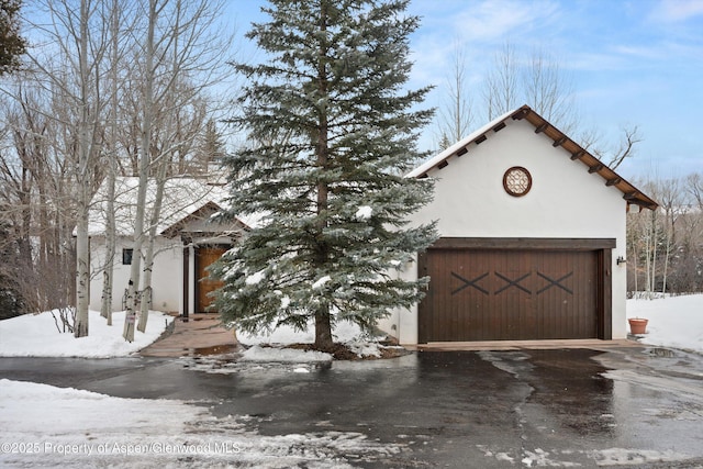 rustic home featuring stucco siding and concrete driveway
