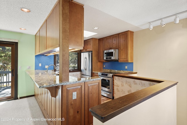 211 Meadow Ranch Dr Unit D5A, Snowmass Village, CO 81615 - kitchen with stainless steel appliances, a peninsula, a textured ceiling, dark stone counters, and recessed lighting