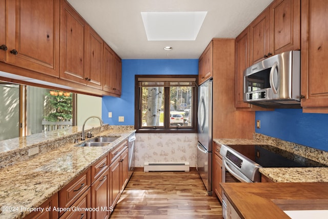 211 Meadow Ranch Dr Unit D5A, Snowmass Village, CO 81615 - kitchen featuring stainless steel appliances, a sink, a baseboard heating unit, wood finished floors, and a skylight