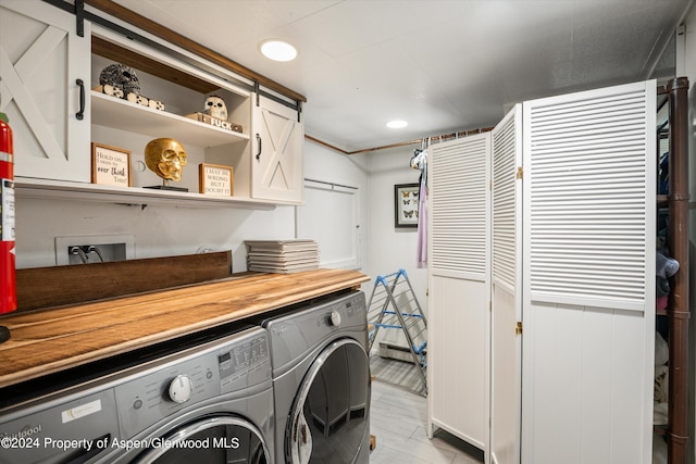 laundry room featuring cabinets, a barn door, and washing machine and dryer