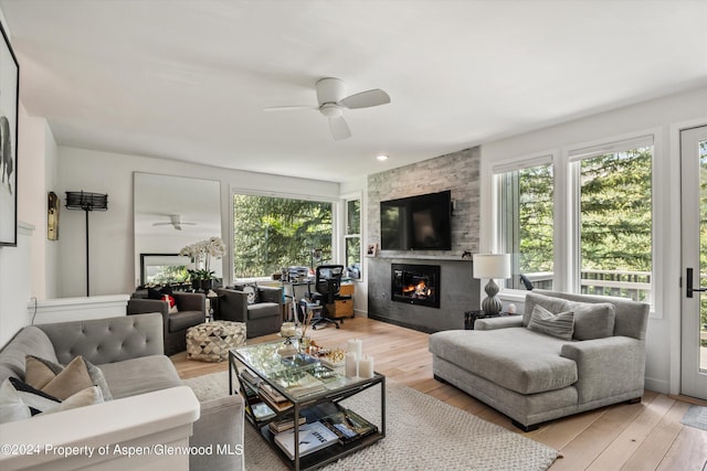 living room with ceiling fan, a large fireplace, and light wood-type flooring