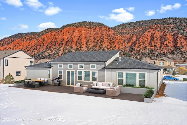 back of property featuring an outdoor living space with a fire pit and a deck with mountain view