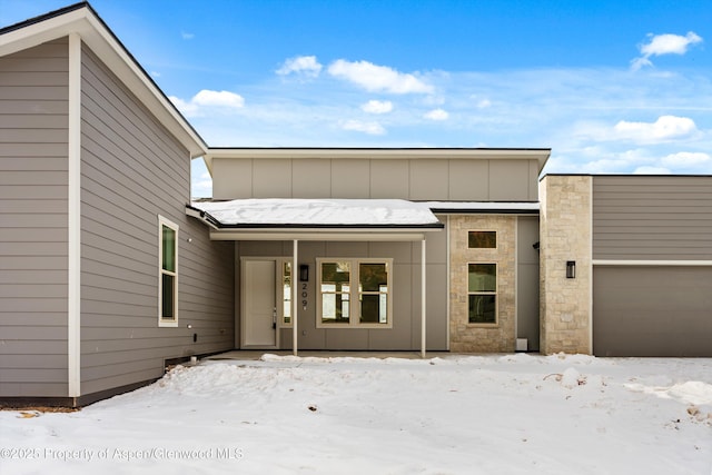 snow covered property entrance featuring a garage