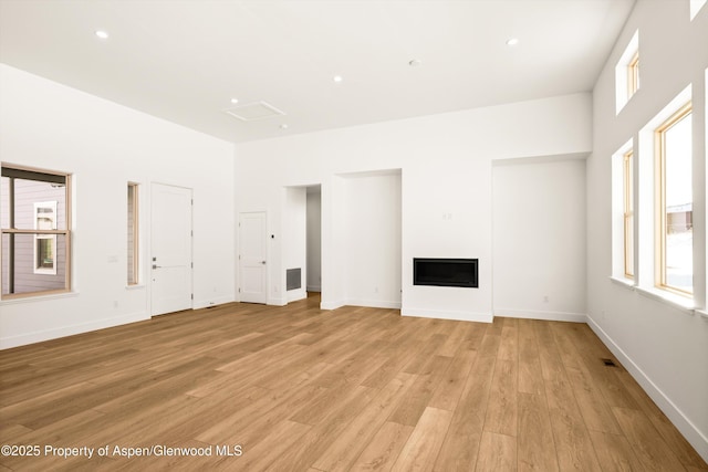 unfurnished living room featuring a towering ceiling and light wood-type flooring