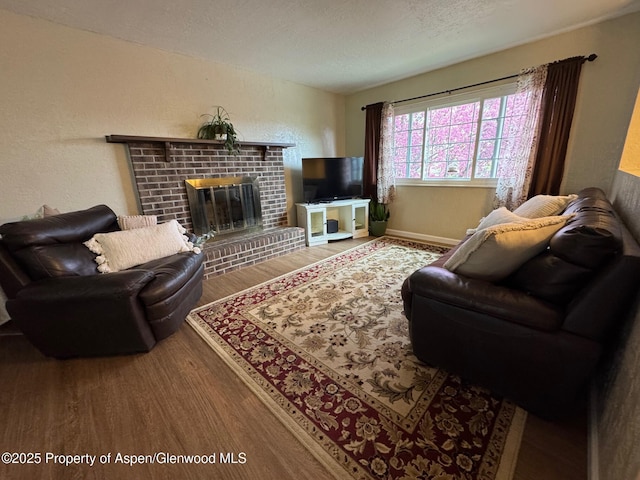 living room featuring a textured ceiling, wood finished floors, a fireplace, and a textured wall