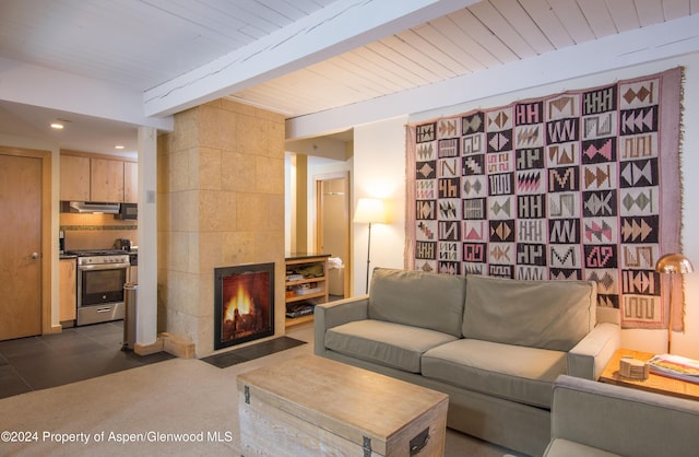 living room featuring wooden ceiling, a tile fireplace, dark tile patterned floors, tile walls, and beam ceiling