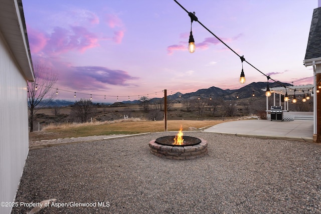 yard at dusk with a mountain view, a fire pit, and a patio area