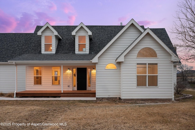 cape cod house featuring roof with shingles and covered porch