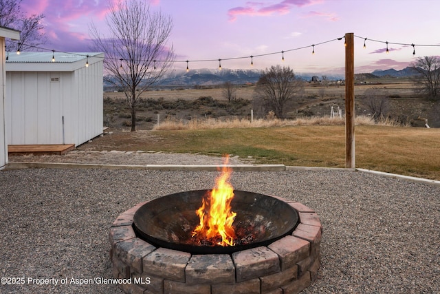 view of yard with an outbuilding, a shed, a mountain view, and an outdoor fire pit