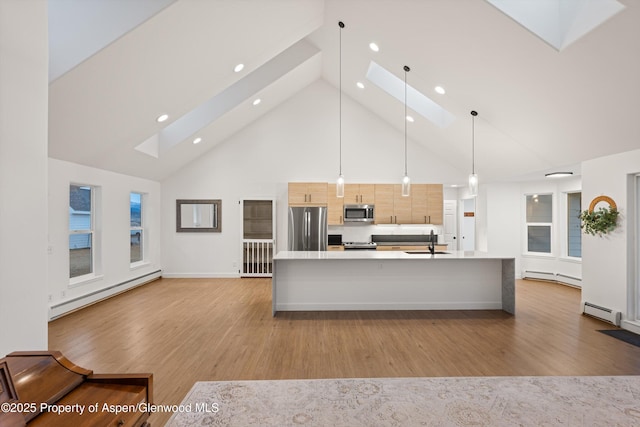 kitchen featuring a sink, a skylight, appliances with stainless steel finishes, and a baseboard radiator