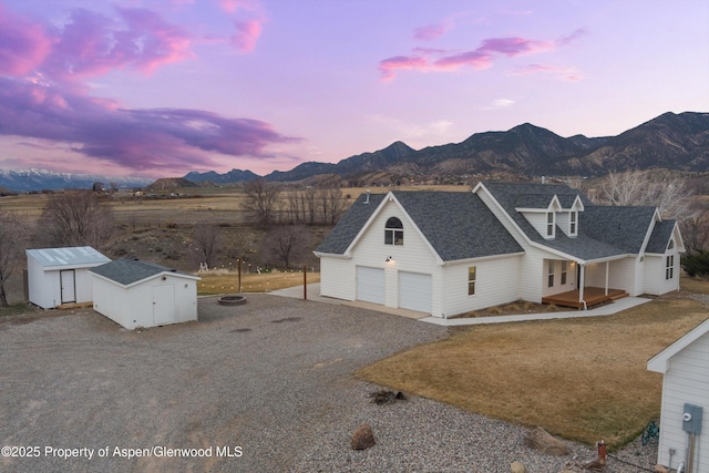 exterior space with roof with shingles, a storage shed, a garage, an outbuilding, and a mountain view