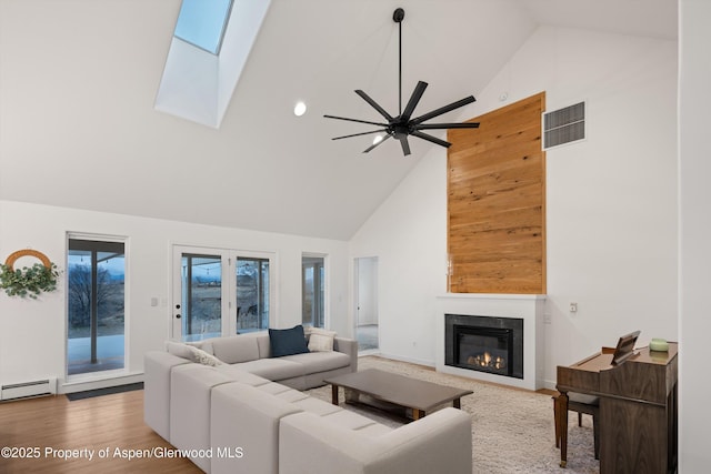 living room featuring visible vents, baseboard heating, a glass covered fireplace, and high vaulted ceiling