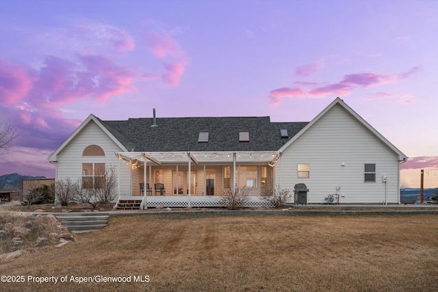 rear view of house with a lawn and a shingled roof