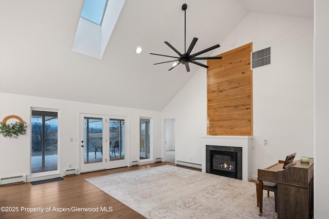 living area featuring baseboard heating, a skylight, visible vents, and a glass covered fireplace