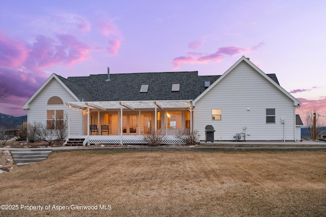 back of house featuring a lawn and a shingled roof