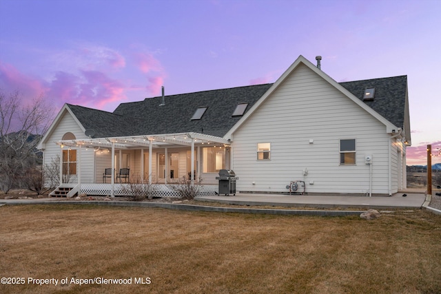 back of house at dusk with a yard, a patio, a shingled roof, and a pergola