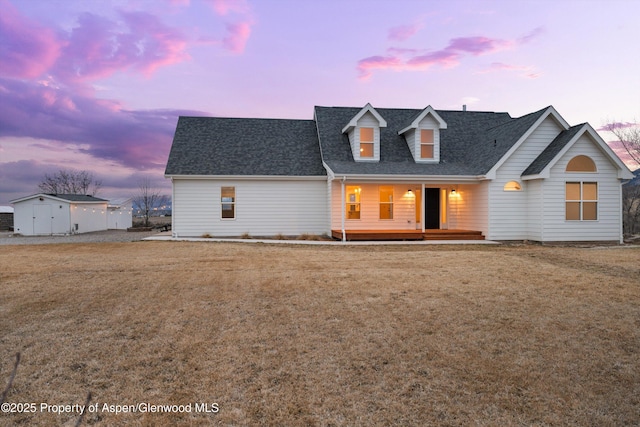 view of front of home with a lawn, covered porch, and a shingled roof