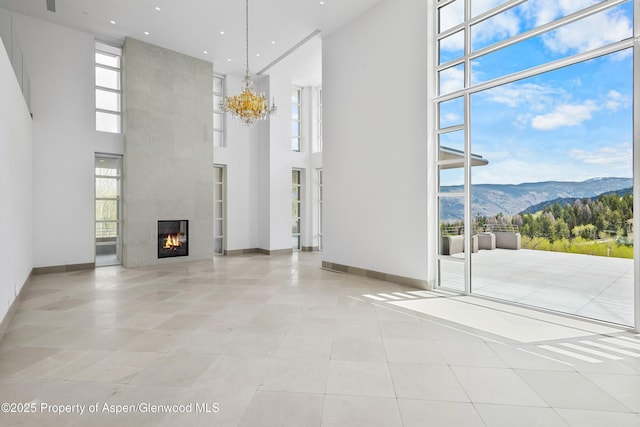401 Eagle Park Dr, Aspen, CO 81611 - unfurnished living room featuring a mountain view, a high ceiling, healthy amount of natural light, a large fireplace, and baseboards