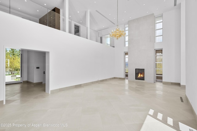 401 Eagle Park Dr, Aspen, CO 81611 - unfurnished living room featuring a towering ceiling, plenty of natural light, a chandelier, a large fireplace, and baseboards