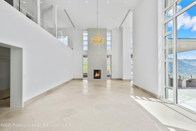 401 Eagle Park Dr, Aspen, CO 81611 - spare room featuring a high ceiling, a chandelier, light tile patterned flooring, a large fireplace, and baseboards