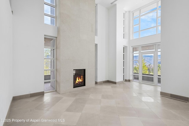 401 Eagle Park Dr, Aspen, CO 81611 - unfurnished living room featuring a high ceiling, plenty of natural light, a fireplace, baseboards, and tile patterned flooring