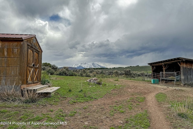 view of yard with a mountain view, a rural view, and an outdoor structure