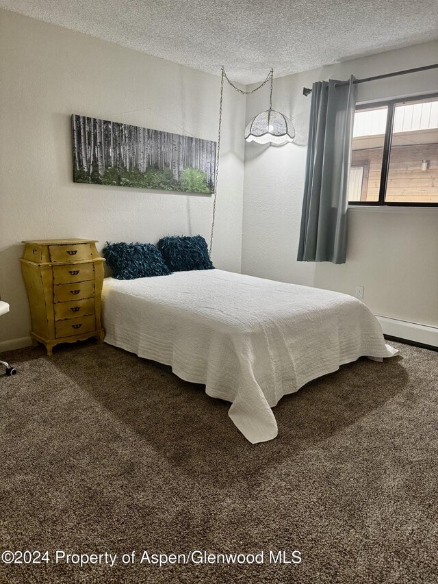 carpeted bedroom with a baseboard radiator and a textured ceiling