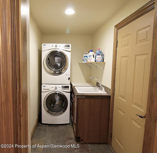 washroom with cabinets, sink, and stacked washer and dryer