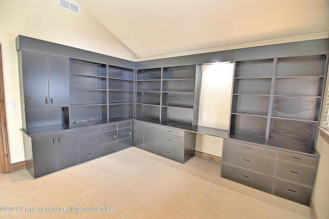 unfurnished office with light carpet, built in desk, and lofted ceiling