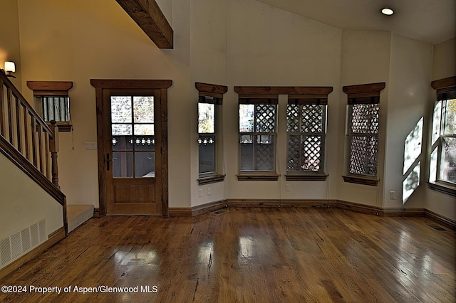 entrance foyer featuring beam ceiling, a high ceiling, and dark hardwood / wood-style floors