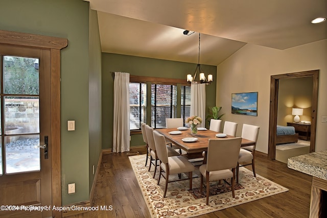 dining area with lofted ceiling, dark wood-type flooring, and an inviting chandelier