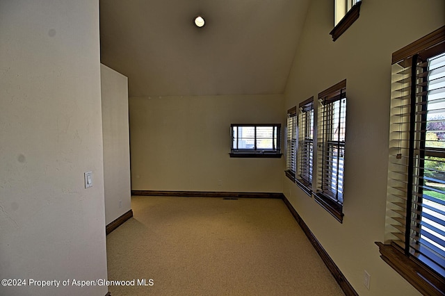 carpeted empty room with high vaulted ceiling