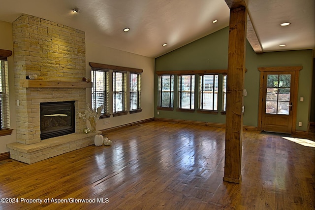 unfurnished living room with dark hardwood / wood-style floors, a stone fireplace, and lofted ceiling