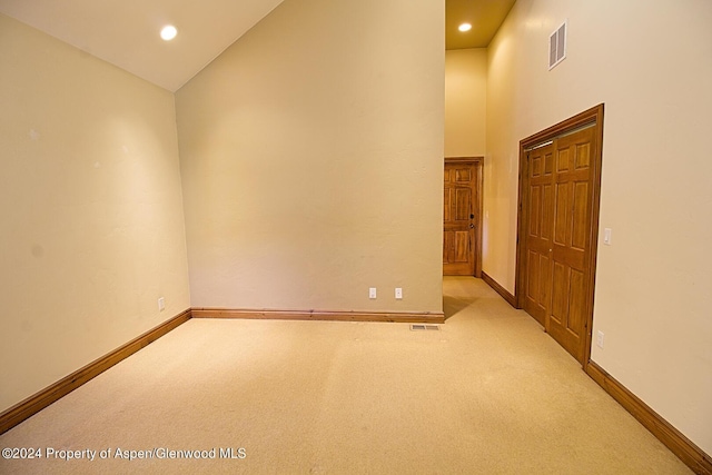 empty room featuring light colored carpet and high vaulted ceiling