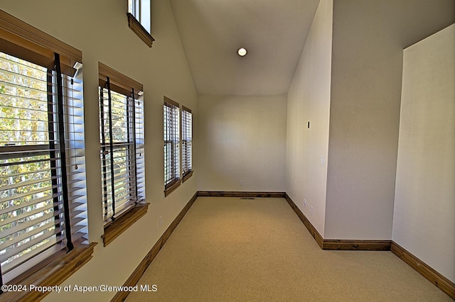 corridor featuring carpet floors and high vaulted ceiling