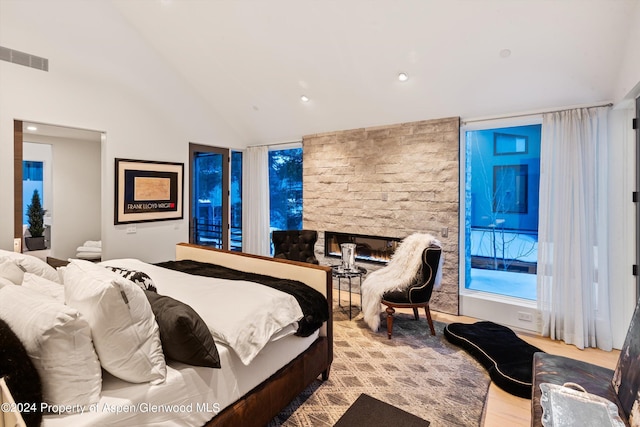 bedroom featuring a stone fireplace and high vaulted ceiling