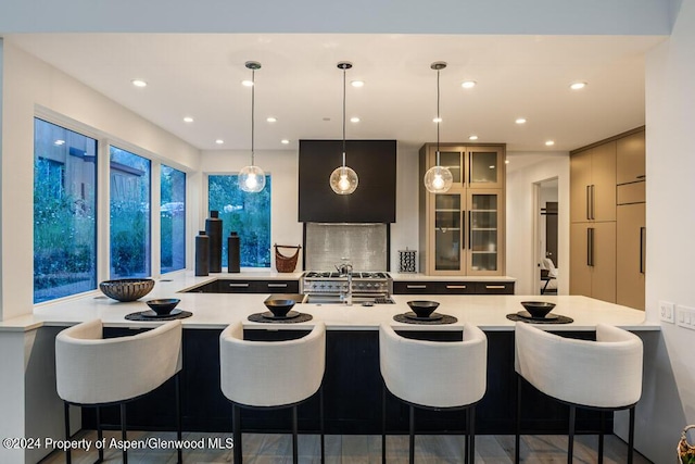 kitchen with a kitchen breakfast bar, kitchen peninsula, sink, and pendant lighting