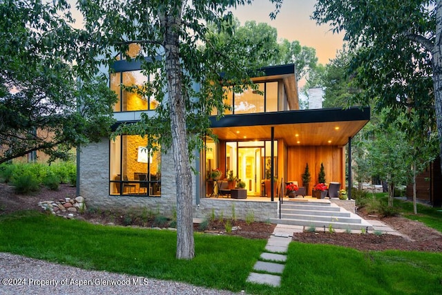 back house at dusk featuring a yard