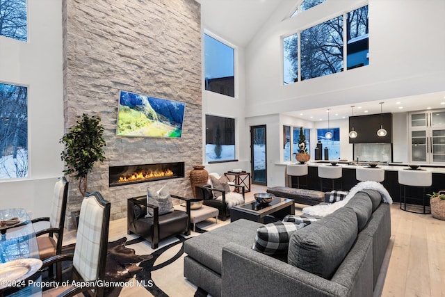 living room featuring a fireplace, a high ceiling, and light hardwood / wood-style flooring