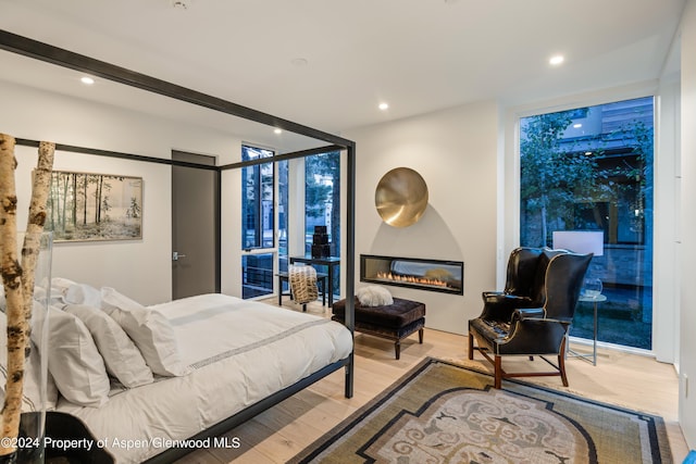 bedroom with light wood-type flooring and a wall of windows