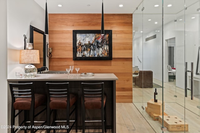 bar featuring light hardwood / wood-style flooring and wood walls