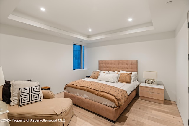 bedroom featuring light hardwood / wood-style floors and a raised ceiling