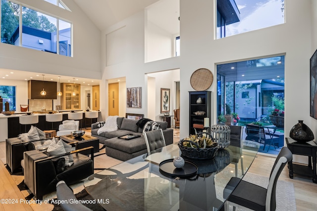 dining space with a towering ceiling and light hardwood / wood-style floors