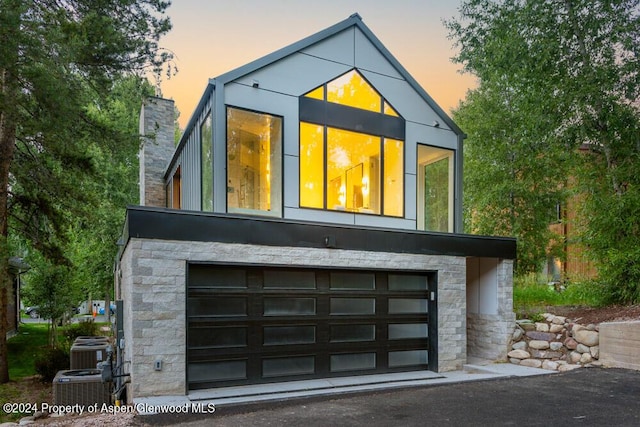 property exterior at dusk with a garage and central AC