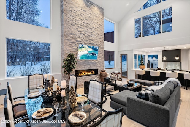 living room with light hardwood / wood-style floors, a stone fireplace, and high vaulted ceiling