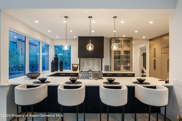 kitchen with kitchen peninsula, hanging light fixtures, a breakfast bar area, and sink