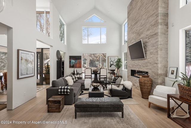 living room featuring a fireplace, a high ceiling, and light hardwood / wood-style flooring