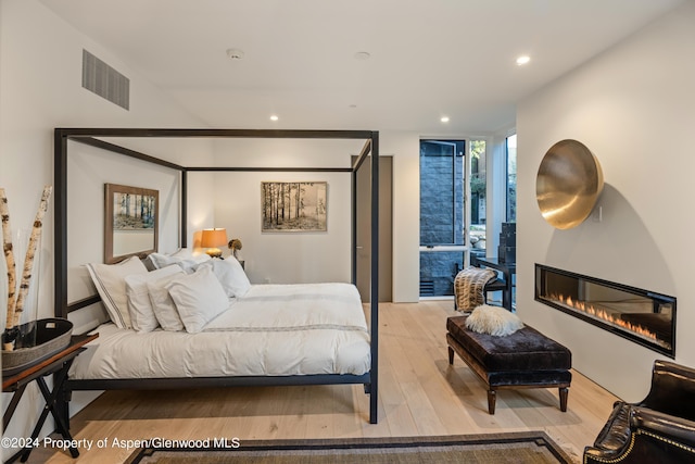 bedroom with a large fireplace and light hardwood / wood-style floors