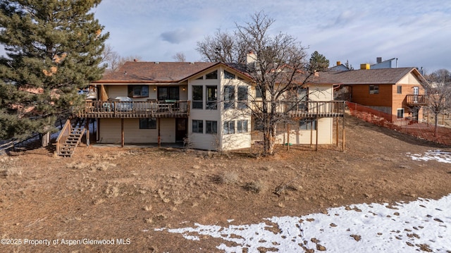 snow covered rear of property featuring a deck