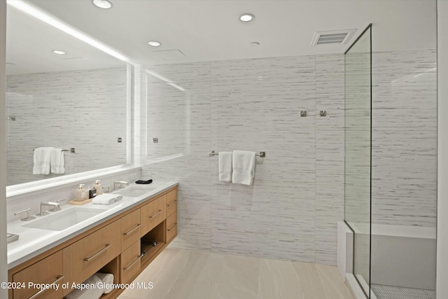 bathroom featuring a tile shower, tile patterned floors, vanity, and tile walls